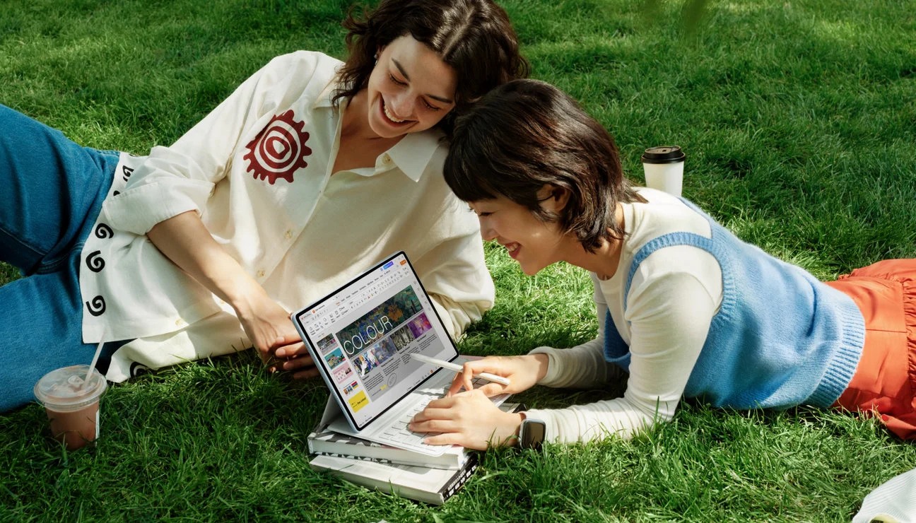 Two people viewing a HUAWEI MatePad Air on a keyboard stand outdoors in a manufacturer illustration.